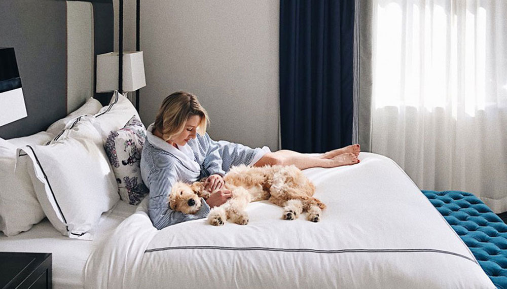 woman hugging dog while lying in bed