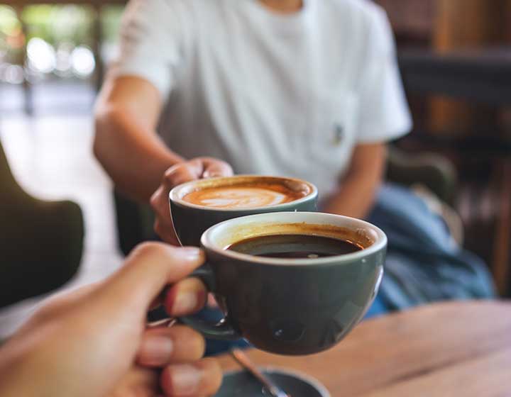two people cheersing with coffee